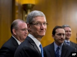 Apple CEO Tim Cook, center, is surrounded by his team during a break from testifying on Capitol Hill in Washington, May 21, 2013.