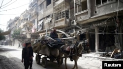People are seen with their belongings in the besieged town of Douma, Eastern Ghouta, in Damascus, Syria, March 8, 2018. 