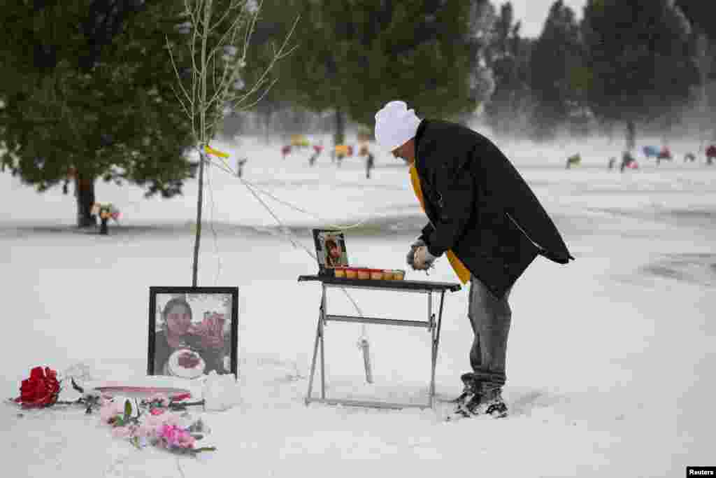 Antonio Cervantes brings gifts to the grave of his wife Gabriela, who died of the coronavirus disease (COVID-19), for Valentine&#39;s Day, at a cemetery in Santa Teresa, New Mexico, Feb. 14, 2021.