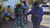 Collin Nkadimeng, left, barters with a customer Tuesday outside of the Medi-Clinic Heart Hospital in Pretoria, where former South African President Nelson Mandela has been treated since June 8. (Photo: Peter Cox / VOA)