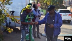 Collin Nkadimeng, left, barters with a customer Tuesday outside of the Medi-Clinic Heart Hospital in Pretoria, where former South African President Nelson Mandela has been treated since June 8. (Photo: Peter Cox / VOA)