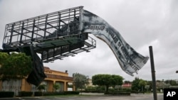 A billboard canvas flaps in the wind after Hurricane Matthew passed off shore, Oct. 7, 2016, in North Palm Beach, Fla. 