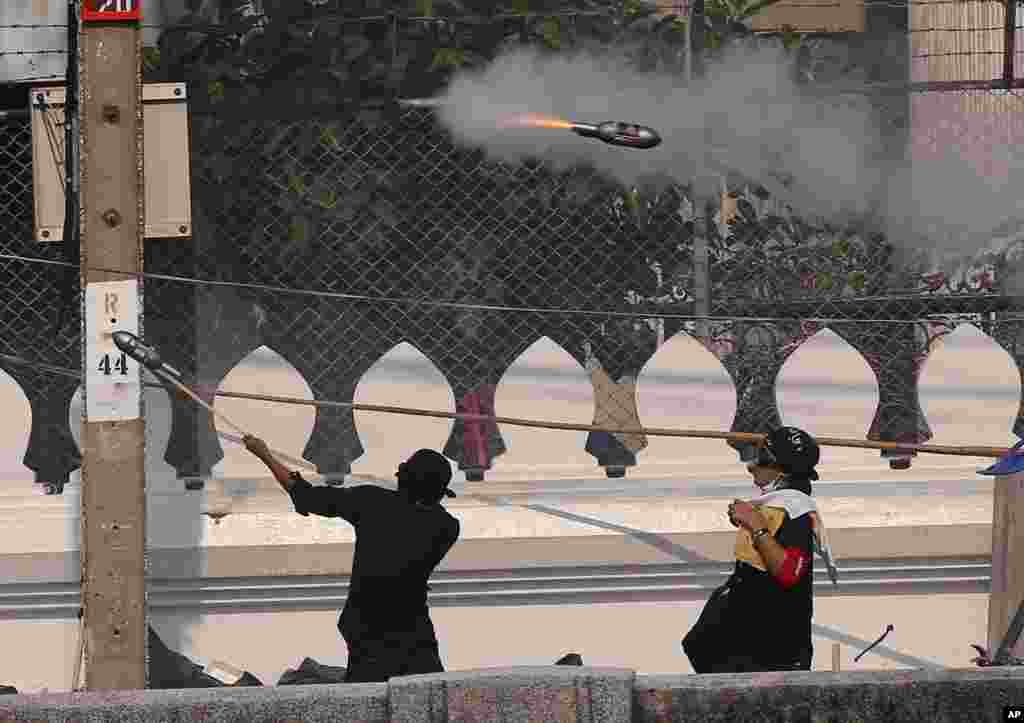 Manifestantes anti-governo usam rockets artesanais num motim frente à polícia, em Banguecoque, Tailândia. 