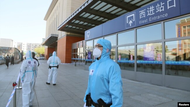 中国吉林省吉林市身穿防护服的警察站在停运的火车站进站口处。(2020年5月13日)