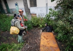 Diggers Andriy Ryshtun and Oleksandr Ivanov and historian Hanna Tychka prepare to go underground to explore the city sewage system. REUTERS/Gleb Garanich