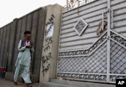 FILE - A man looks at graffiti supporting the Islamic State group as he walks past an entrance of a compound in Karachi, Pakistan, Nov. 12, 2014. Hate roams freely online "while the state chases poets, artists and journalists,” one critic wrote on Twitter.