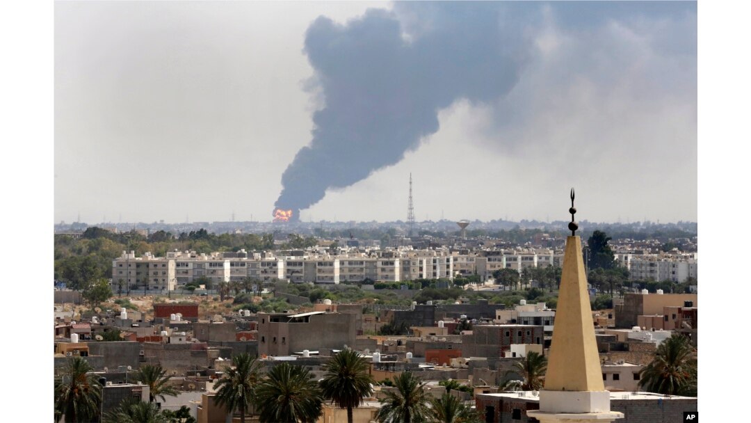 FILE - Black smoke billows over the skyline as a fire at the oil depot for the airport rages out of control, in Tripoli, July 28, 2014.