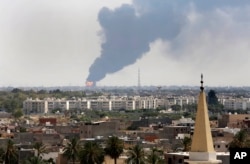 FILE - Black smoke billows over the skyline as a fire at the oil depot for the airport rages out of control, in Tripoli, July 28, 2014.