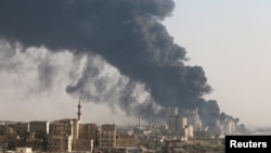 Pemandangan kota Aleppo menunjukan asap hitam naik ke udara yang datang dari pabrik semen dibawah kontrol rezim Suriah Selasa (9/8).