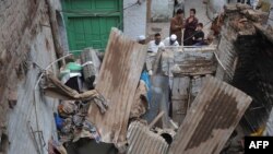 Pakistani residents look at a damaged house following an earthquake in Peshawar, on Oct. 26, 2015. AFP PHOTO / HASHAM AHMED