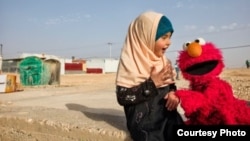 Elmo visits a young girl in a refugee camp. Sesame Workshop, together with the International Rescue Committee, have teamed up in an effort to provide quality education to young children displaced by conflict and persecution. (Photo courtesy of Sesame Workshop)