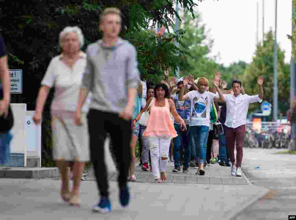 People evacuated after shooting in a shopping mall walk with hands up on July 22, 2016 in Munich.