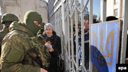 Ukraine -- A Ukrainian woman speaks with armed men in military uniform, believed to be Russian Soldiers, who block Ukrainian navy base in Novoozerniy village near of Yevpatoriya, Crimea, March 3, 2014