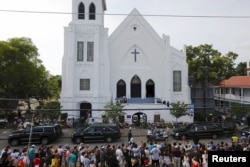 Warga berdiri di tepi jalan menyaksikan iring-iringan yang membawa jenazah Pendeta Clementa Pinckney tiba di depan gereja Emanuel AME, Charleston, South Carolina.