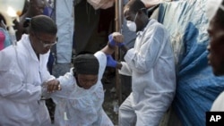 A woman suffering cholera symptoms is helped at an earthquake refugee camp in Port-au-Prince, Haiti, January 8, 2011