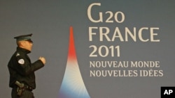 A French police officer walks past the G20 logo and slogan, 'New World, New Ideas,' outside the festival palace as preparations for the G20 summit continue in Cannes, France, November 2, 2011.
