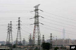 Power grid stand against the residential and office buildings in Beijing as the capital of China is shrouded by mild pollution haze on June 5, 2017.