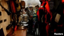 A migrant child helps crew members prepare a meal on the migrant search and rescue ship Sea-Watch 3, operated by German NGO Sea-Watch, off the coast of Malta in the central Mediterranean Sea, Jan. 3, 2019. 