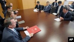 FILE - Britain's Secretary of State for International Trade Liam Fox, bottom left, and Japanese Minister of Economic Revitalization Toshimitsu Motegi, right, attend a meeting in Tokyo, July 31, 2018.