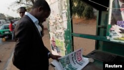 FILE - A man looks at a newspaper at a news stand in Abuja. Nigeria's military repelled multiple attacks by suspected Boko Haram militants on Borno state capital Maiduguri, Jan. 26, 2015. 