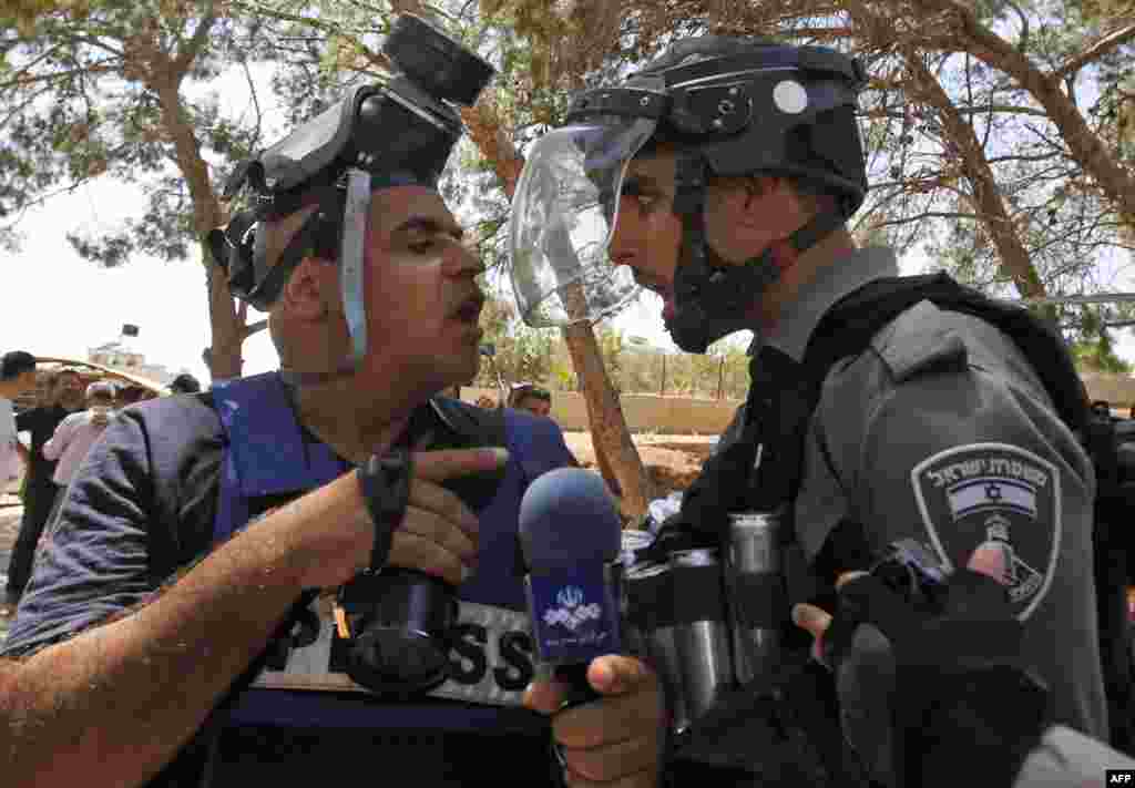 An Israeli border police confronts a journalist following clashes after the Friday prayers at the site of demolished buildings in Dar Salah, the West Bank, near Sur Baher in East Jerusalem.