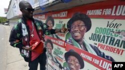 A man points to campaign posters of Nigerian President Goodluck Jonathan and candidate of the ruling People's Democratic Party (PDP) in Lagos, Nigeria, March 21, 2015. 