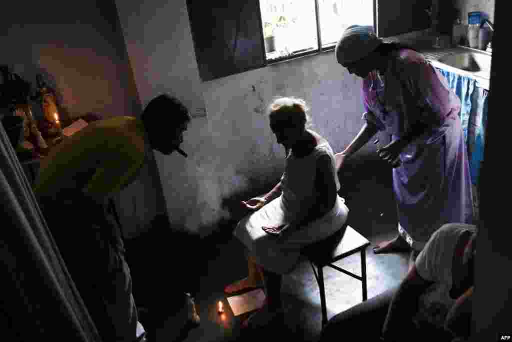 Esperanza Castillo (C), 74, is treated at the clinic of spiritual healer &quot;Guayanese Brother&quot; in Petare neighborhood, Caracas. Venezuelans turn to alternative treatments and the use of herbs to alleviate the disease conditions due to the lack or high cost of medicines.