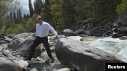 FILE - During a visit to Kyrgyzstan, Russia's President Vladimir Putin crosses a stream in Ala-Archa National Park, south of Bishkek, May 28, 2013.