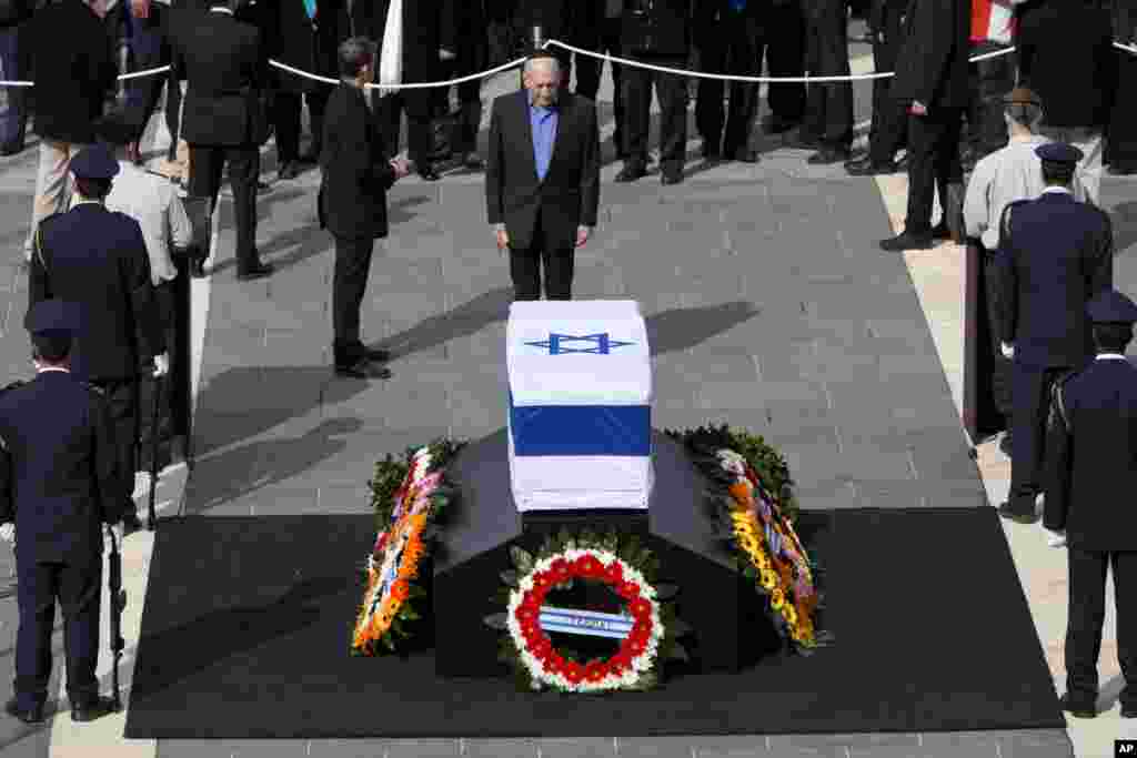 Former Israeli Prime Minister Ehud Olmert pays his respect at the coffin of former Israeli Prime Minister Ariel Sharon at the Knesset Plaza, in Jerusalem, January 12, 2014. 