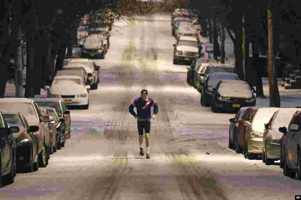 A jogger makes his way along a snow-covered street in the Hudson Park neighborhood in Albany, New York.