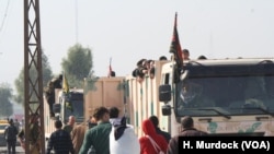 2016年11月7日，在摩苏尔城外，男子们爬上军用卡车前往难民营。（美国之音希瑟·默多克拍摄）