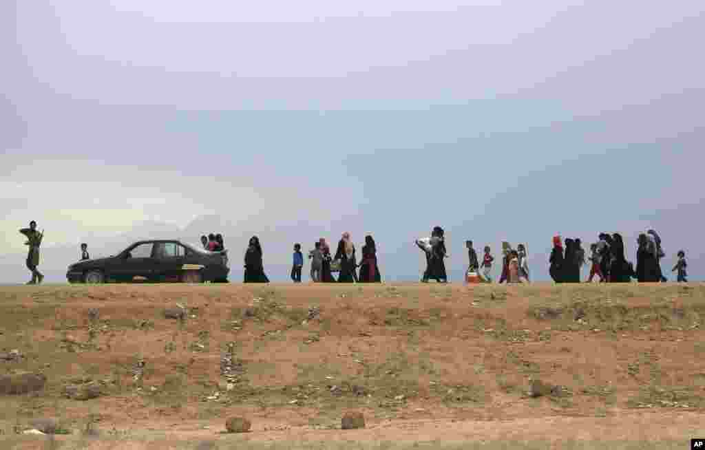 People flee their homes during fighting between Iraqi security forces and the Islamic State group during a military operation to regain control of Hit, 85 miles (140 kilometers) west of Baghdad, Iraq, April 13, 2016.