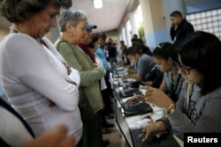 People register to cast their vote at a polling station during a legislative election, in Caracas, Venezuela, Dec. 6, 2015.