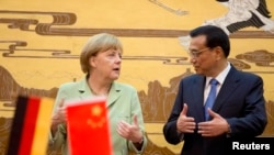 German Chancellor Angela Merkel (L) chats with Chinese Premier Li Keqiang during the signing ceremony at the Great Hall of the People in Beijing, July 7, 2014.