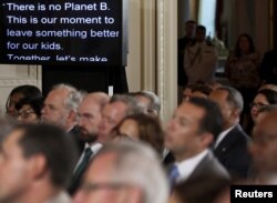 FILE - US President Barack Obama's remarks are shown on large monitors in the East Room as he addresses climate change and the Clean Power Plan at the White House in Washington, Aug. 3, 2015.