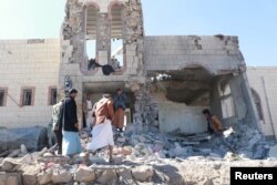 People inspect damage at the site of air strikes in the northwestern city of Saada, Yemen December 20, 2017.