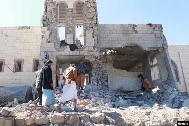 People inspect damage at the site of air strikes in the northwestern city of Saada, Yemen December 20, 2017.