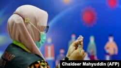 Seorang petugas kesehatan bersiap untuk memberikan vaksin Sinovac melawan Covid-19 di Rumah Sakit Zainoel Abidin di Banda Aceh pada 21 Januari 2021. (Foto: AFP/Chaideer Mahyuddin)