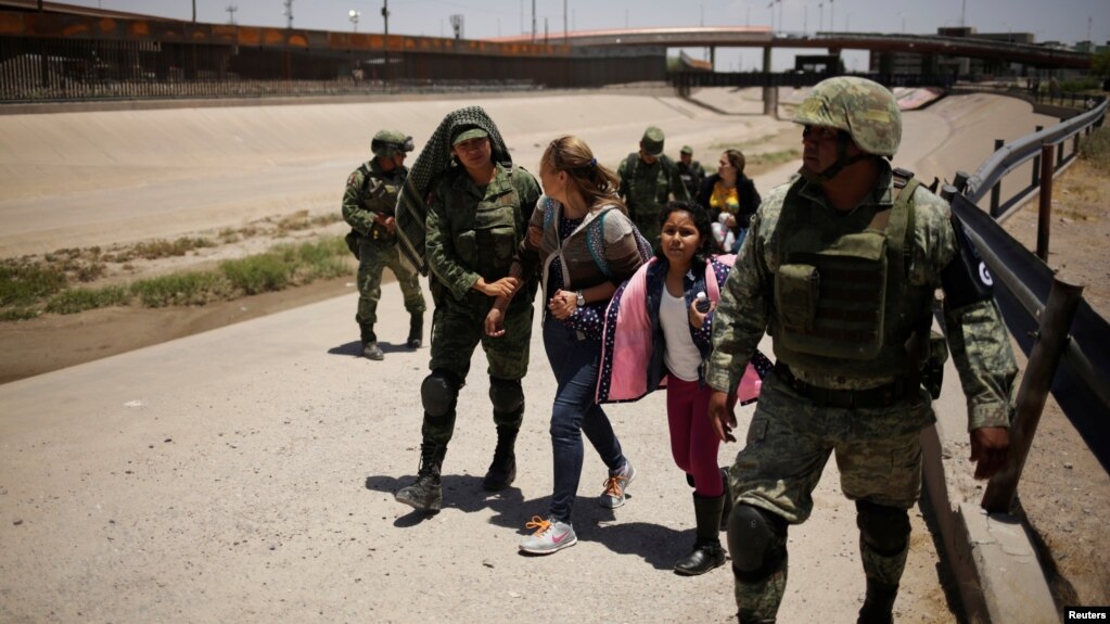 Miembros de la Guardia Nacional de México escoltan a una mujer nicaraguense y su hija después de detenerlas cuando intentaban cruzar ilegalmente la frontera entre los Estados Unidos y México, en Ciudad Juárez, México, 21 de junio de 2019. REUTERS / Jose Luis Gonzalez.