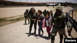 Miembros de la Guardia Nacional de México escoltan a una mujer nicaraguense y su hija después de detenerlas cuando intentaban cruzar ilegalmente la frontera entre los Estados Unidos y México, en Ciudad Juárez, México, 21 de junio de 2019. REUTERS / Jose Luis Gonzalez.