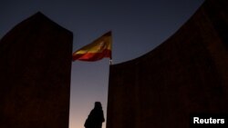 A woman stands near a Spanish flag in Plaza Colon (Columbus Square) on the eve of regional elections in Catalonia in Madrid, Dec. 20, 2017. 