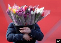 This man carries a bucket of tulips in Minsk, Belarus, March 7, 2019.