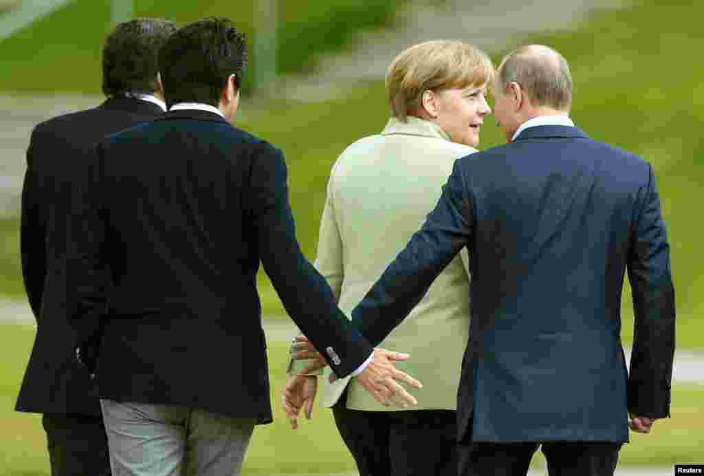 Japan&#39;s Prime Minister Shinzo Abe (2nd L) touches hands with Russia&#39;s President Vladimir Putin as they walk with Germany&#39;s Chancellor Angela Merkel at the Lough Erne golf resort in Enniskillen, Northern Ireland.