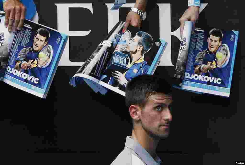 Novak Djokovic of Serbia walks past magazines featuring pictures of himself as he signs autographs after winning the men&#39;s singles match against Leonardo Mayer of Argentina at the Australian Open 2014 tennis tournament in Melbourne, Australia.