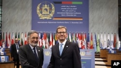German Foreign Minister Guido Westerwelle, right, and his Afghan counterpart Salmai Rassul shake hands as they visit the World Conference Centre Bonn (WCCB) , Germany, December 3, 2011.