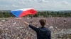یک مرد با پرچم جمهوری چک در مقابل دهها هزار معترض شهر پراگ. 