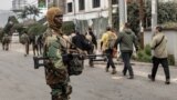 (FILE) A member of the M23 armed group monitors as men believed to be Romanian military contractors line up near the border post crossing into Rwanda, in Goma on January 29, 2025.