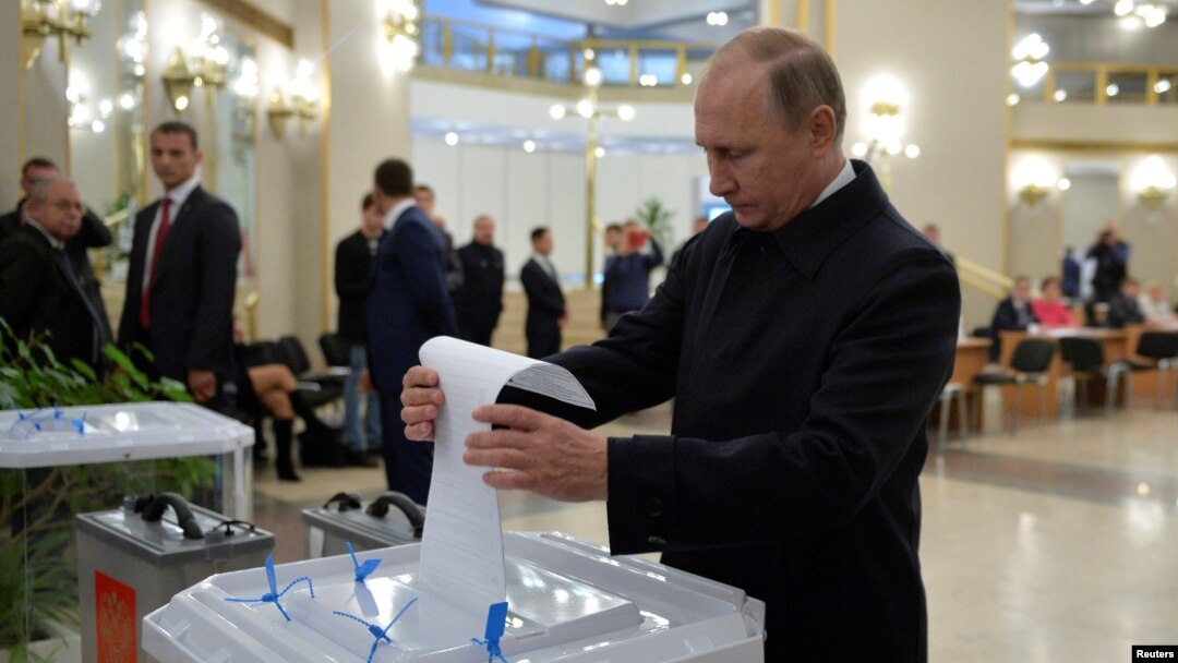 Presiden Rusia Vladimir Putin memasukkan kartu suara di sebuah TPS di Moskow pada pemilu parlemen hari Minggu (18/9).