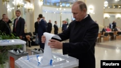 FILE - Russian President Vladimir Putin casts a ballot at a polling station during a parliamentary election in Moscow, Sept. 18, 2016.