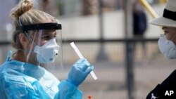 Nurse practitioner Debbi Hinderliter, left, collects a sample from a woman at a coronavirus testing site in San Diego, California, Aug. 13, 2020.